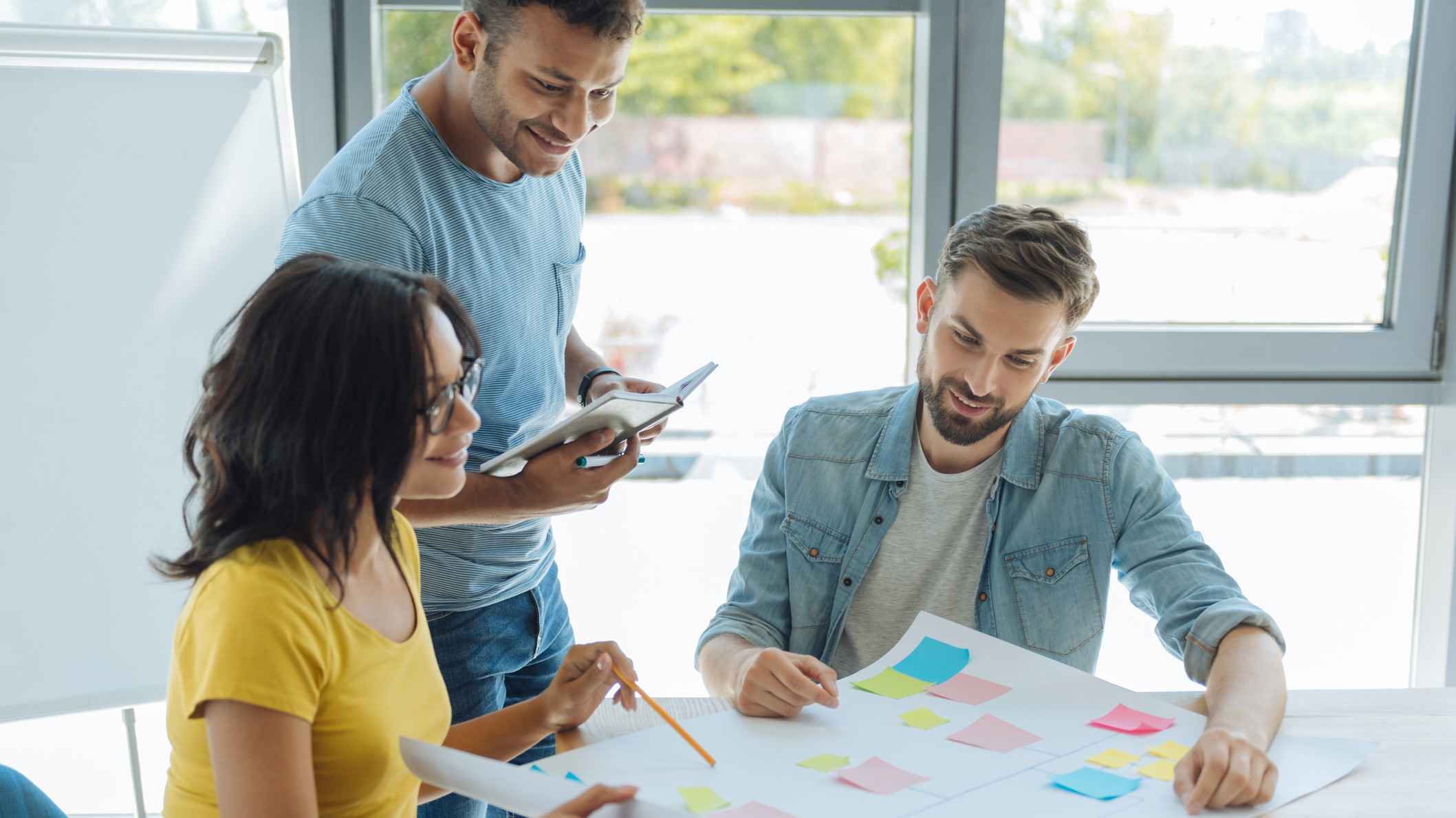 Drei Erwachsene betrachten ein Plakat und reden miteinander
