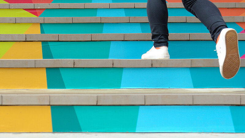 Lower part of teenage girl in casual shoe walking up outdoor colorful stair,teenage lifestyle successful concept