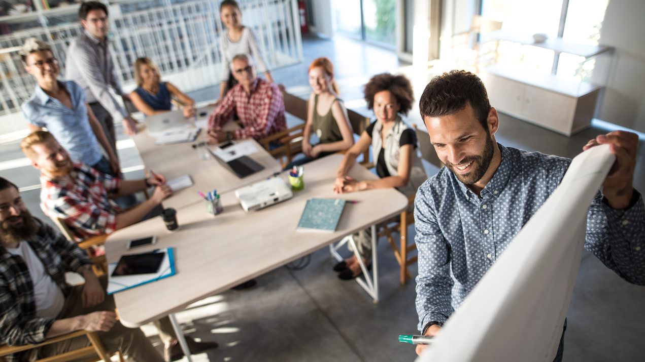 Mann erklärt in einer Teambesprechung im Büro seine Präsentation