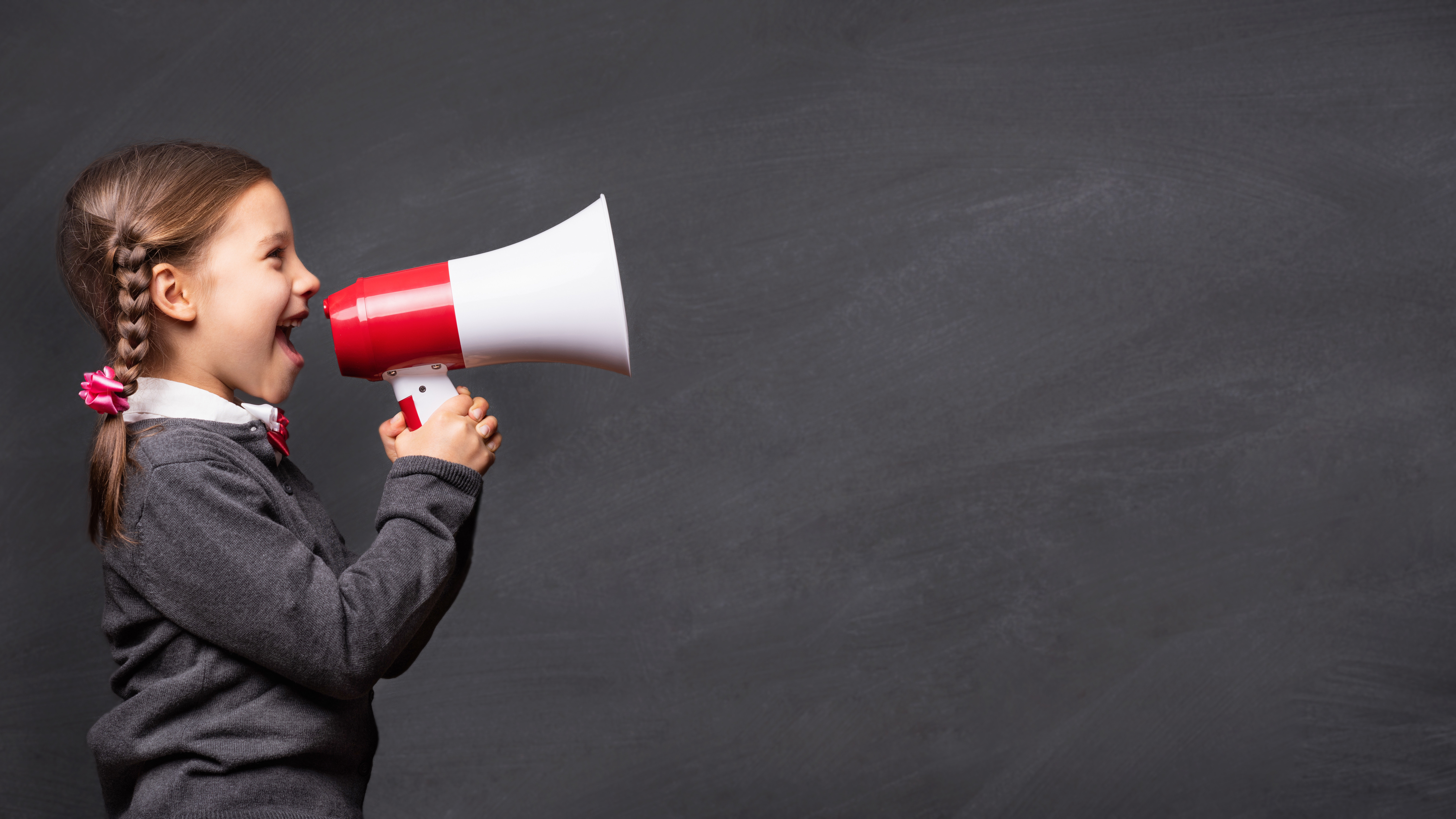 Junge Schülerin, die durch Megaphon spricht.